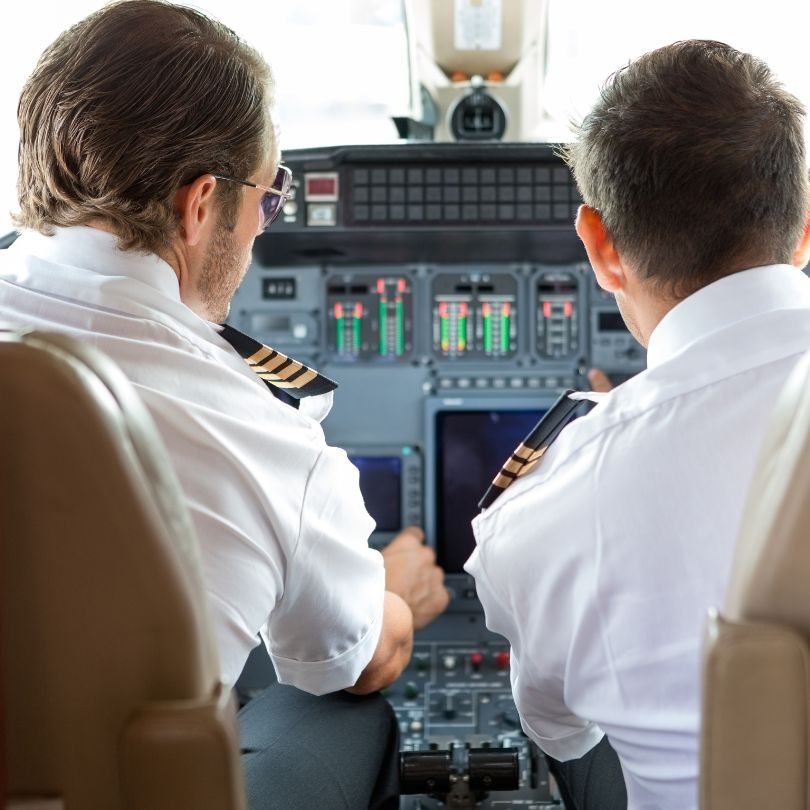 Two pilots conducting pre-flight maintenance checks on a private jet